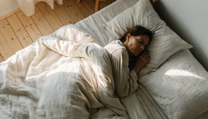 Mujer durmiendo plácidamente en una cama con sábanas blancas