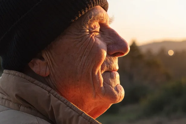 Hombre mayor con gorro de lana mirando al horizonte al atardecer
