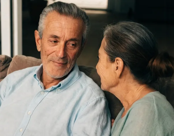 Pareja de personas mayores conversando en el sofá de casa